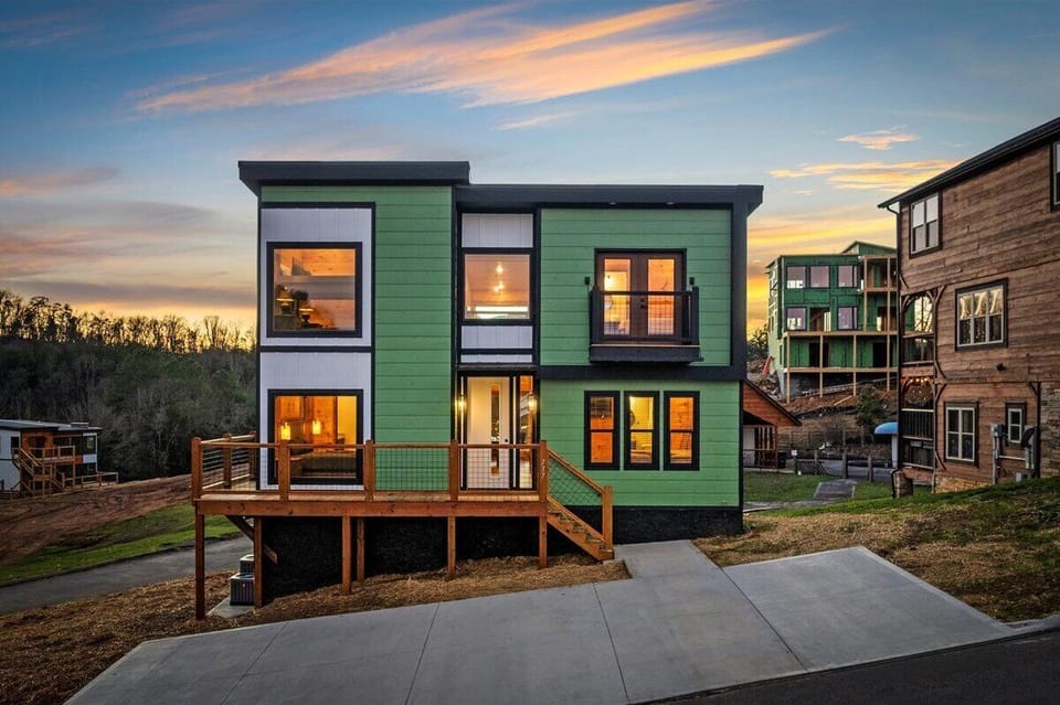 Modern green facade stands bright against the evening sky, creating a stunning arrival experience in this distinctive neighborhood.