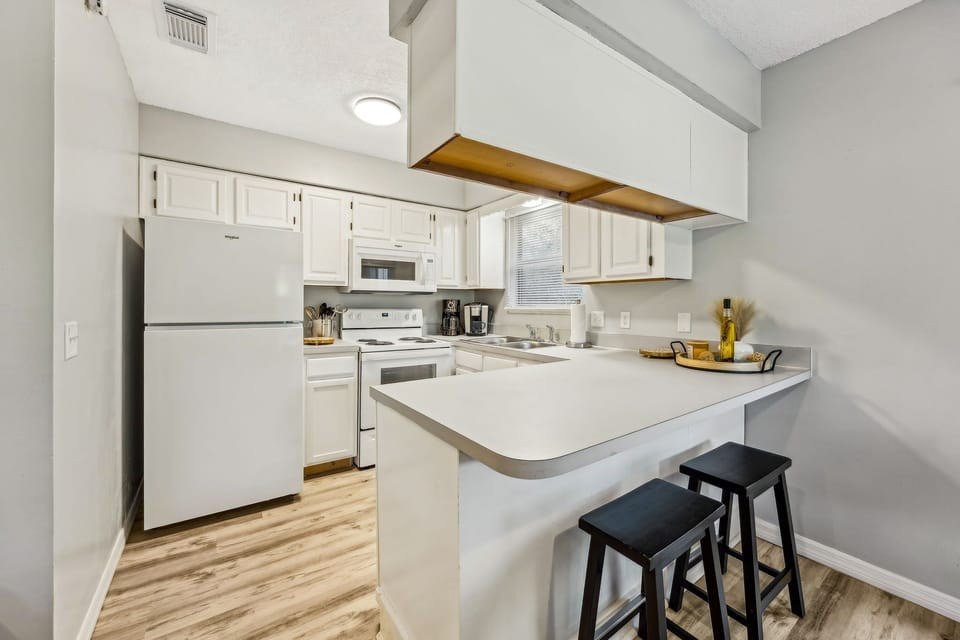 Your fully equipped kitchen features everything needed for home cooking, with white appliances and a convenient breakfast bar for casual dining.