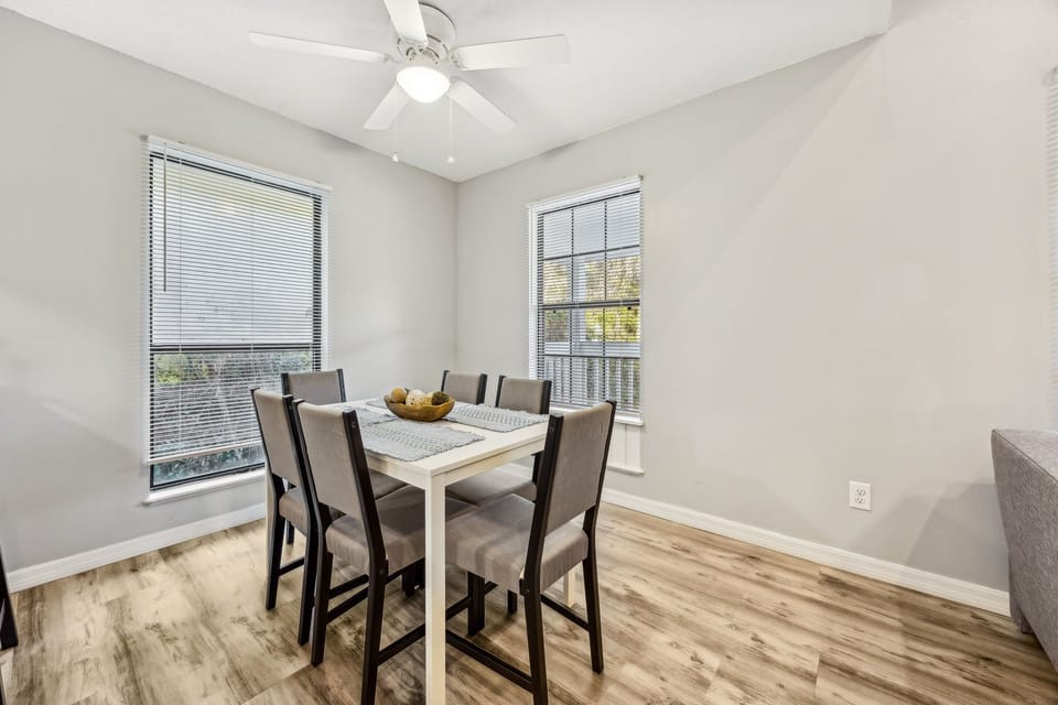 Gather around your bright dining table with natural light streaming through two windows, creating the perfect spot for morning coffee or evening meals together.