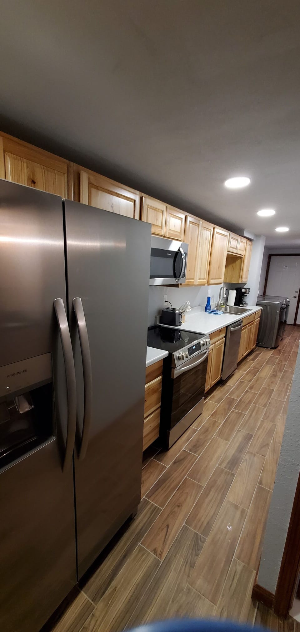Galley kitchen with stove, dishwasher, fridge, microwave and garbage disposal.