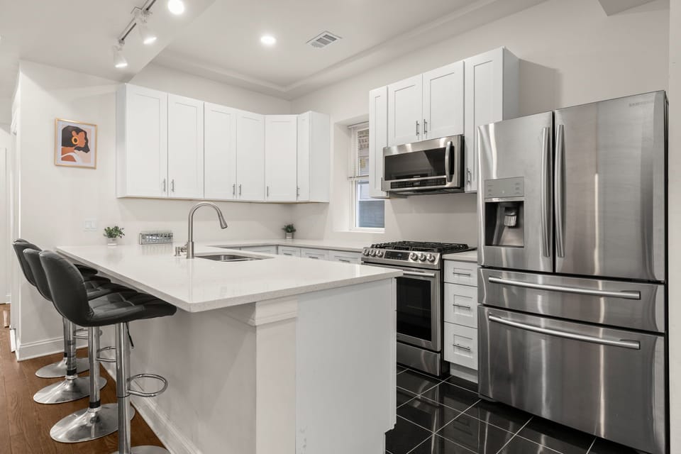 Spacious kitchen with bar seating and stainless steel appliances.