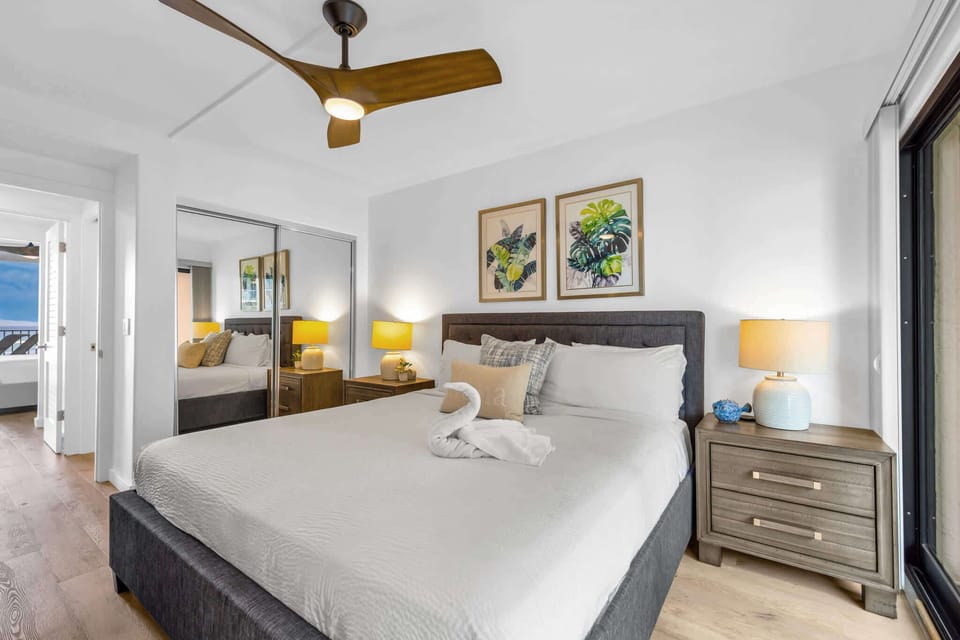 King Ensuite Bedroom – Relax and unpack! Comfortable bed, modern ceiling fan, tropical decor, TV, large mirrored closet, dresser and ensuite bathroom. 