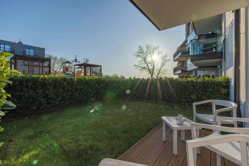 An outdoor terrace with chairs facing a small garden, captured during golden-hour sunlight.