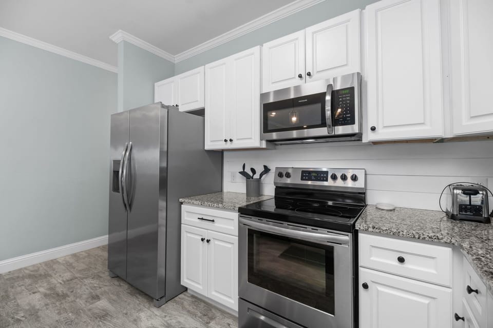 Modern kitchen appliances at Pescador Landing, Perdido Key – stainless steel range, over-the-range microwave, and French door refrigerator. A fully equipped kitchen for your Perdido Key getaway near FloridaBama.