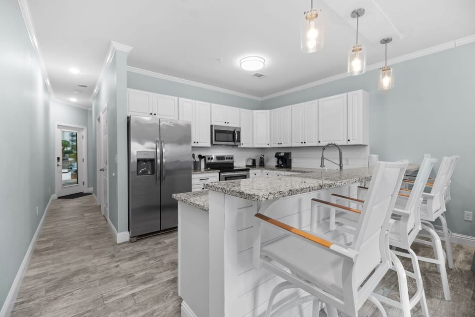 Stylish kitchen with breakfast bar at Pescador Landing, Perdido Key – granite island, pendant lighting, and stainless appliances. Great for entertaining after a fun day near FloridaBama beach.