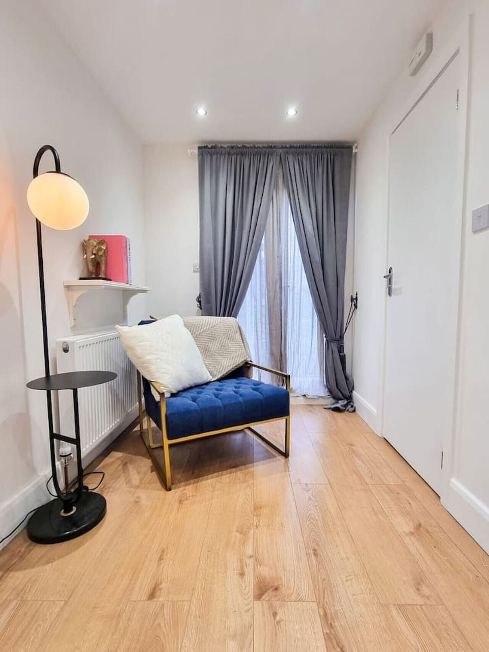 A small seating nook with a floor lamp beside full-length curtains.