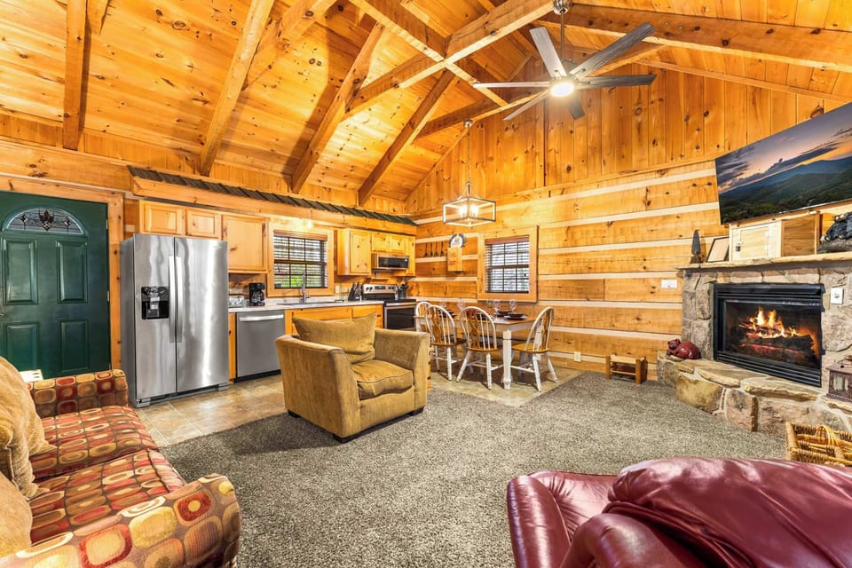 Experience an open-concept living area with vaulted ceilings, a cozy fireplace, and a full kitchen.