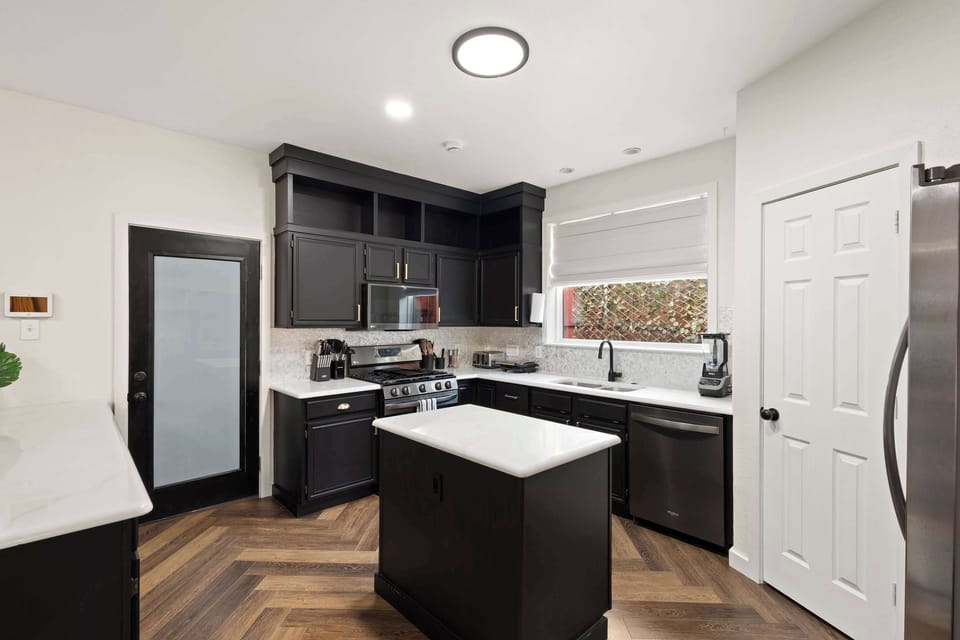 A sleek, modern chef's kitchen featuring high-end stainless steel appliances, dark custom cabinetry, and a central island for easy meal prep.