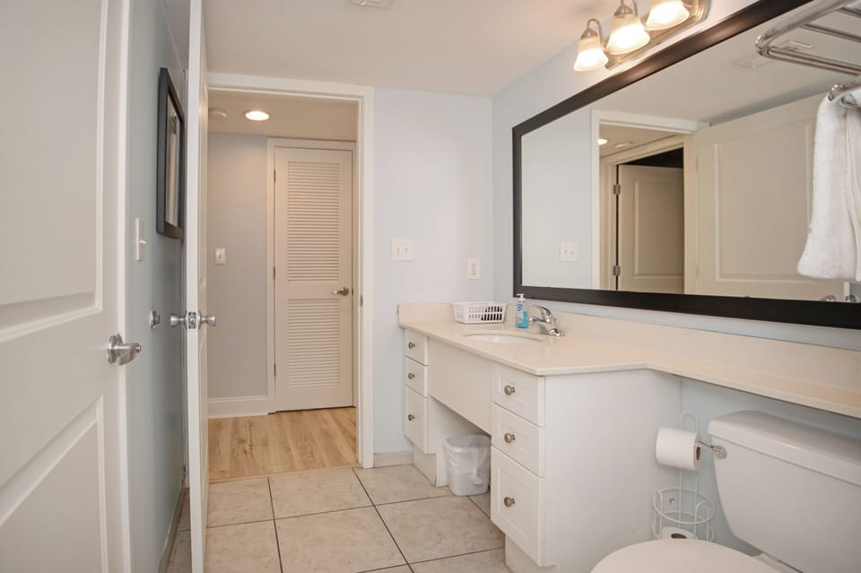 Spacious full bathroom featuring a stylish vanity, towels and basic essentials.