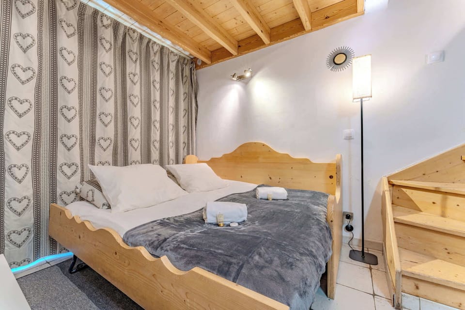 Lit double au rez-de-chaussée, idéal pour se détendre après le ski. Ambiance douce avec rideaux cœur et lumière tamisée.