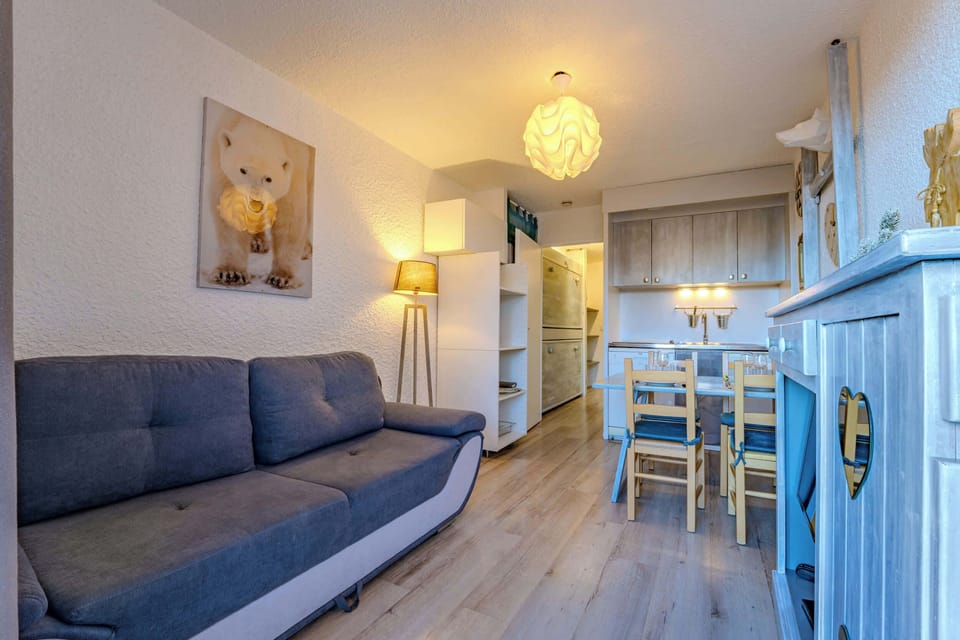 Bright living and dining space with mountain-inspired décor, sofa bed, and balcony access overlooking Val Thorens village.