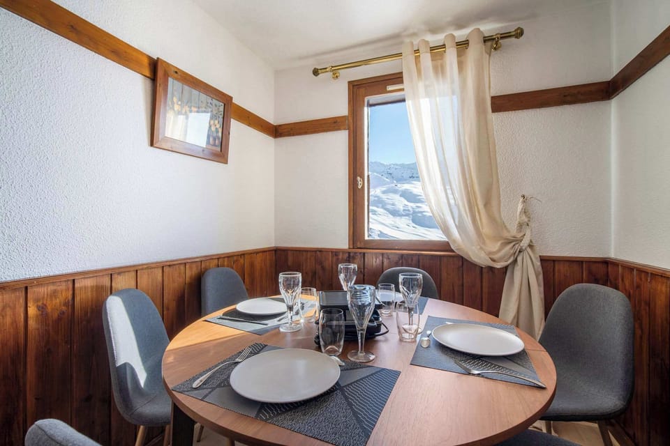 Cozy Alpine dining nook with natural wood décor and panoramic view of the snow-covered peaks.
