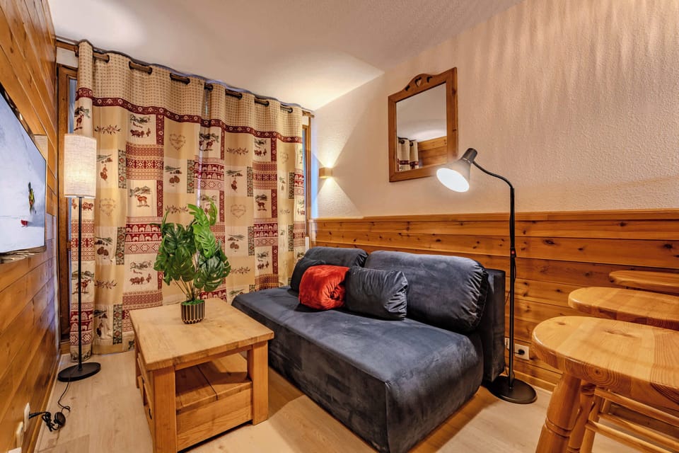 Sunny living room with sofa-bed and large window — Val Thorens studio for 4, steps from slopes, shops and restaurants.