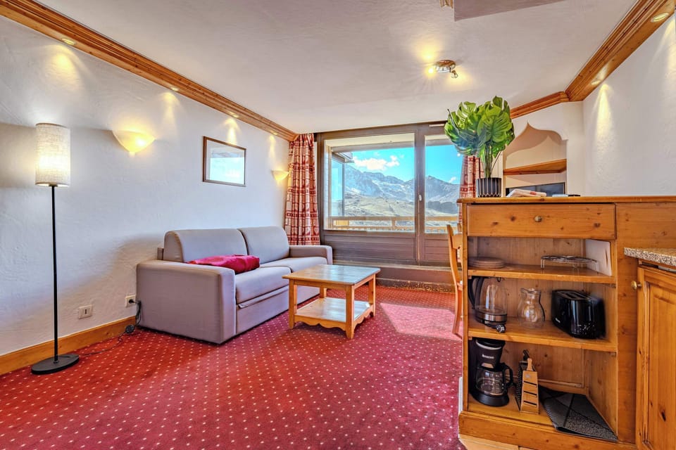 Open-plan lounge with red alpine décor — self-catering Val Thorens apartment near shops & restaurants.