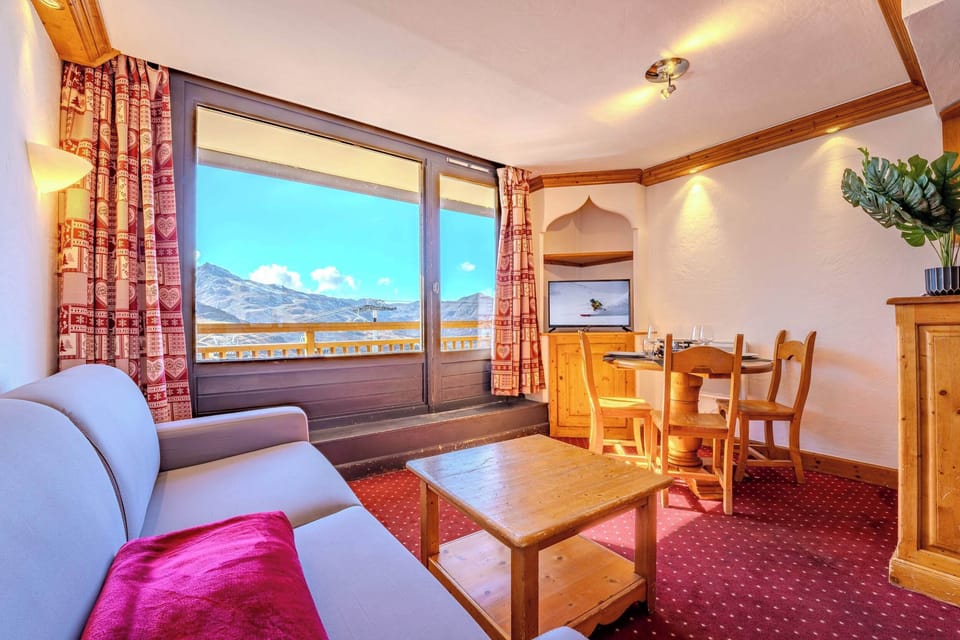 Sofa by picture window — stunning mountain view from ski-in/ski-out Les Belleville apartment.