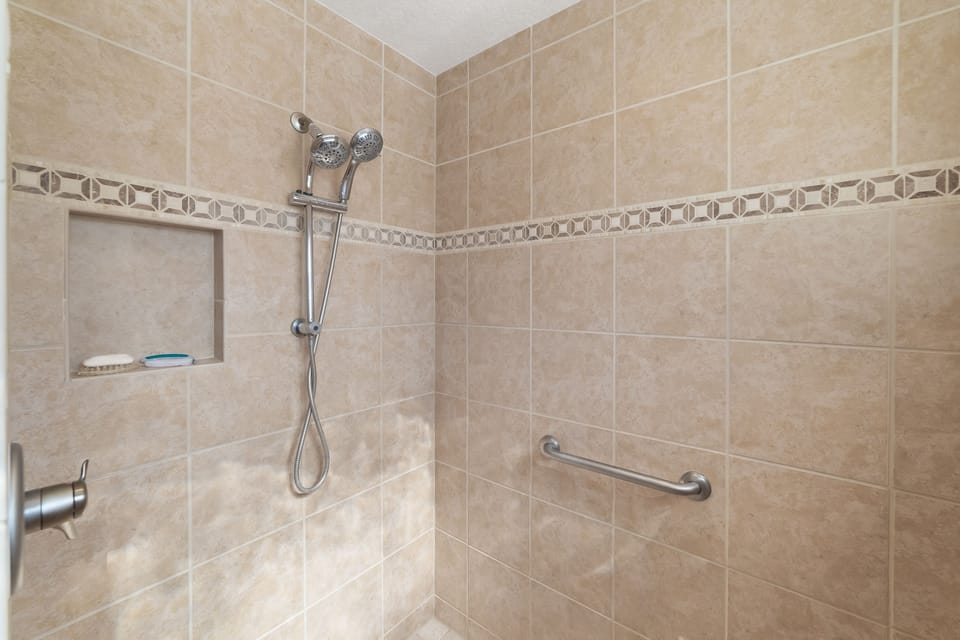 A tiled walk-in shower with dual showerheads and a built-in wall niche.