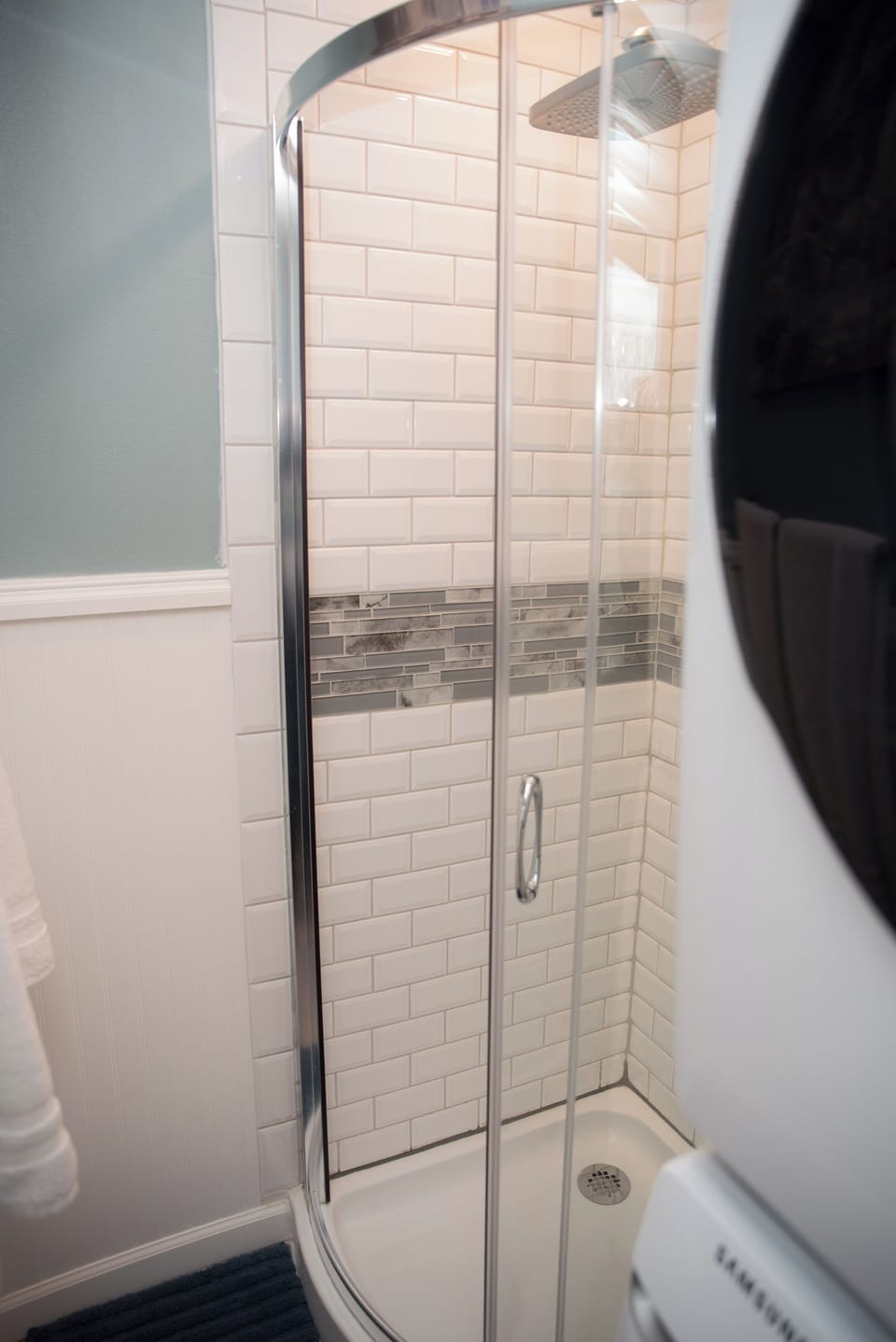 A modern corner shower featuring crisp subway tile and a sleek glass enclosure.
