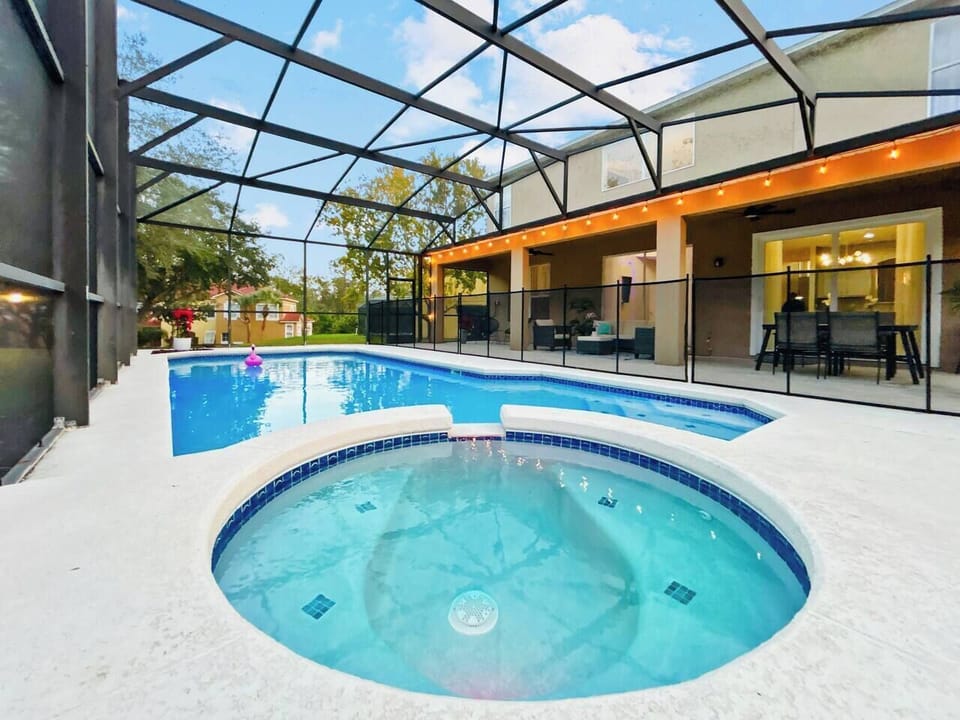 Your private screened-in oasis features a sparkling heated pool and relaxing spa with color-changing LED lights. The spacious covered patio offers plenty of seating for dining or lounging, all surrounded by peaceful greenery.