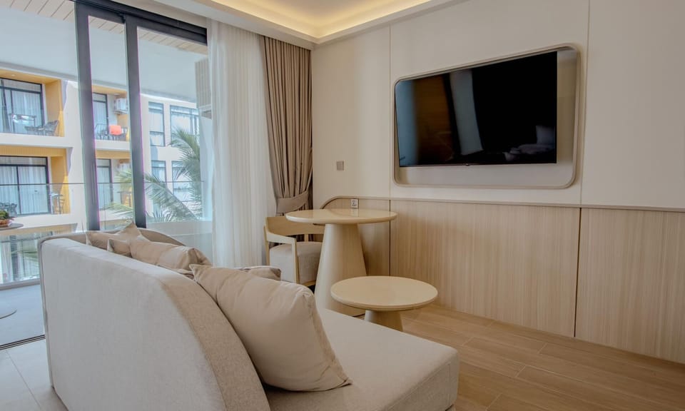 Cozy living area with sofa, flat-screen TV, and natural daylight.