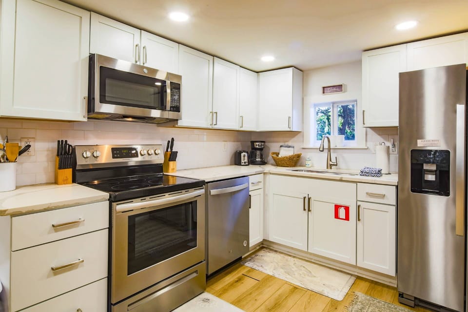 The kitchen features stainless steel appliances, white cabinetry and a tiled backsplash.