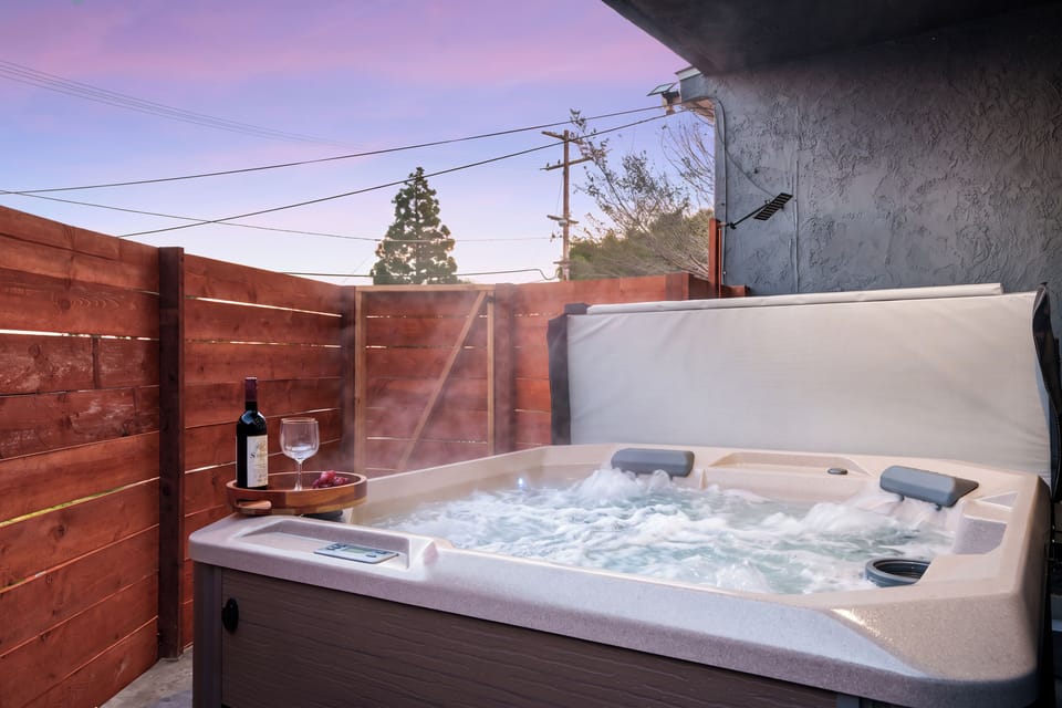 Unwind in the private hot tub tucked behind a privacy fence beneath the evening sky.