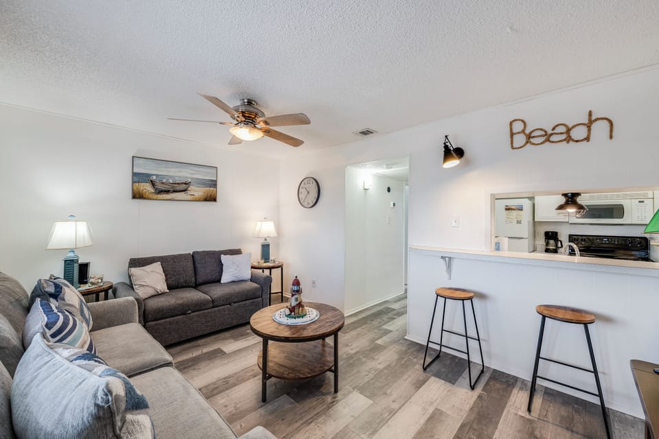 Relax in your coastal-themed living space with comfy seating and open kitchen perfect for beach getaway meals.