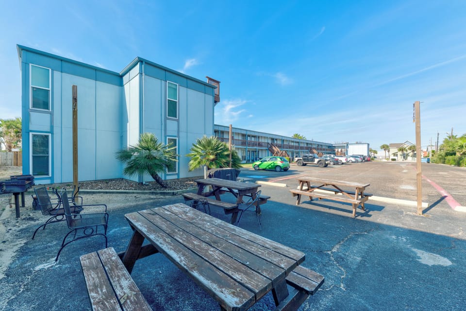 Modern motel property with outdoor picnic tables and palm trees under sunny blue skies.