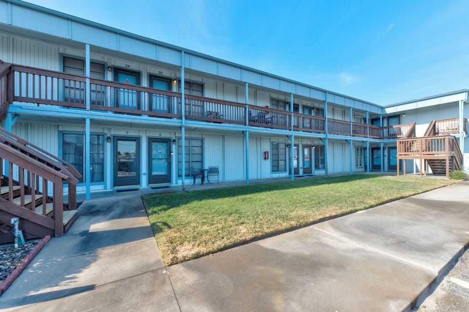 The property's exterior features a classic two-story design with private balconies and convenient ground-level access to numbered guest rooms.