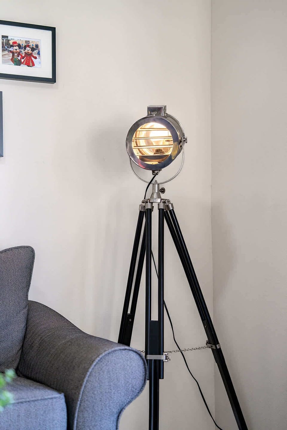 Modern tripod floor lamp adds stylish lighting next to the gray sofa.
