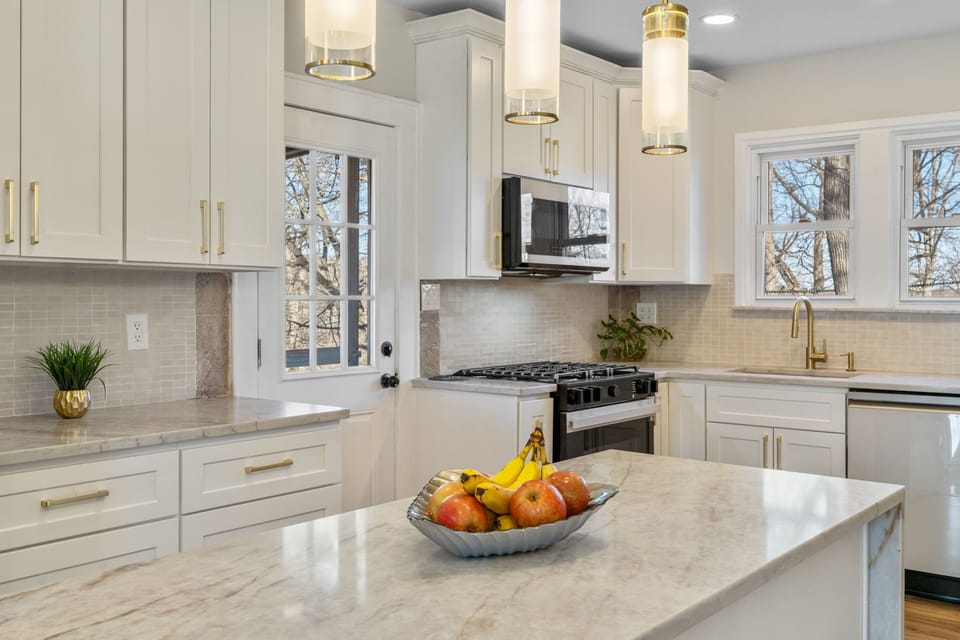 Bright, modern kitchen with a large island and stone countertops. Ideal for meal prep, serving, and casual dining.