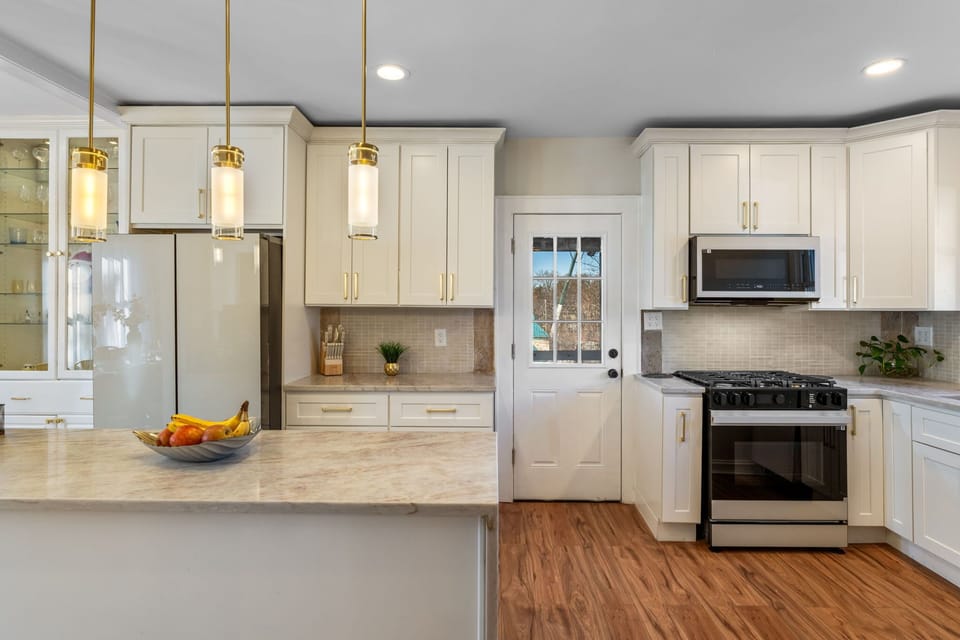Spacious kitchen with white cabinetry, stainless steel appliances, and hardwood floors. Open layout connects seamlessly to the dining area.