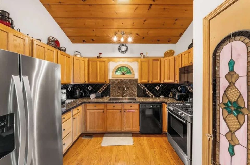 Fully equipped kitchen with warm wood cabinetry, granite countertops, and modern appliances. Spacious layout offers plenty of counter space, making it perfect for preparing meals, family breakfasts, or cozy dinners after a day of exploring.