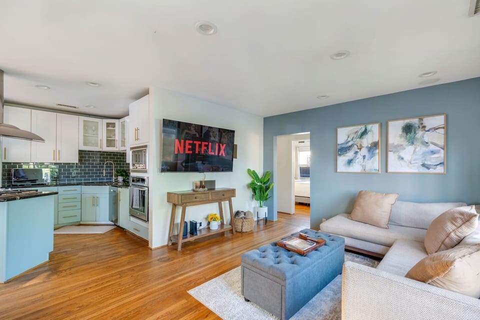Bright living room with cozy sectional, Smart TV, and open-concept kitchen.