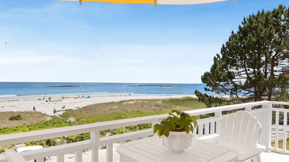 Enjoy breathtaking views of Goose Rocks Beach from the private balcony, complete with comfy seating and vibrant umbrellas perfect for relaxation.