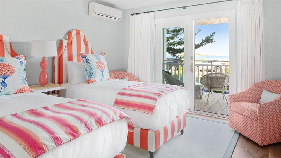 A cheerful bedroom with striped beds and vibrant decor opens to a private balcony, allowing you to indulge in the refreshing coastal breeze.