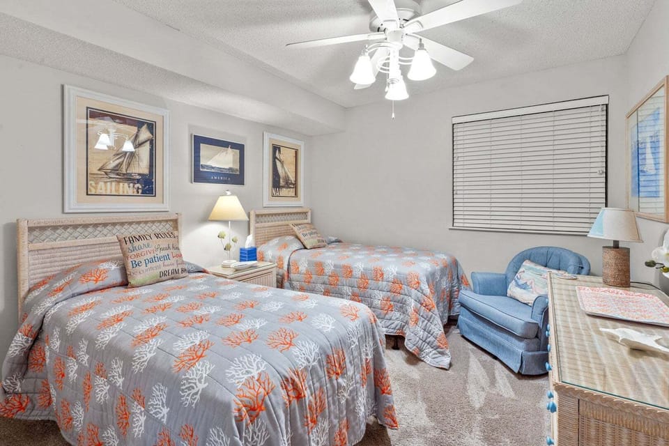 Coral-patterned bedding on two beds with an armchair at Ocean Bay Club 107, a 4-bedroom Ocean Drive rental