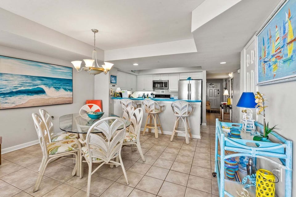 Glass-top dining table and bar stools at the kitchen counter in Ocean Bay Club 107, a 4-bedroom Ocean Drive rental