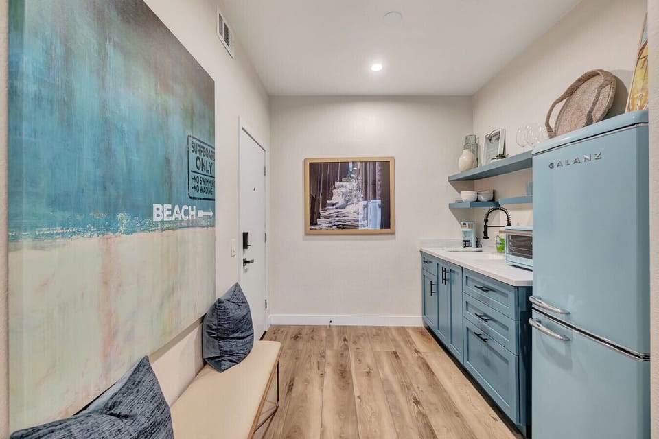 Entryway w/ coastal artwork, blue cabinetry & warm wood flooring