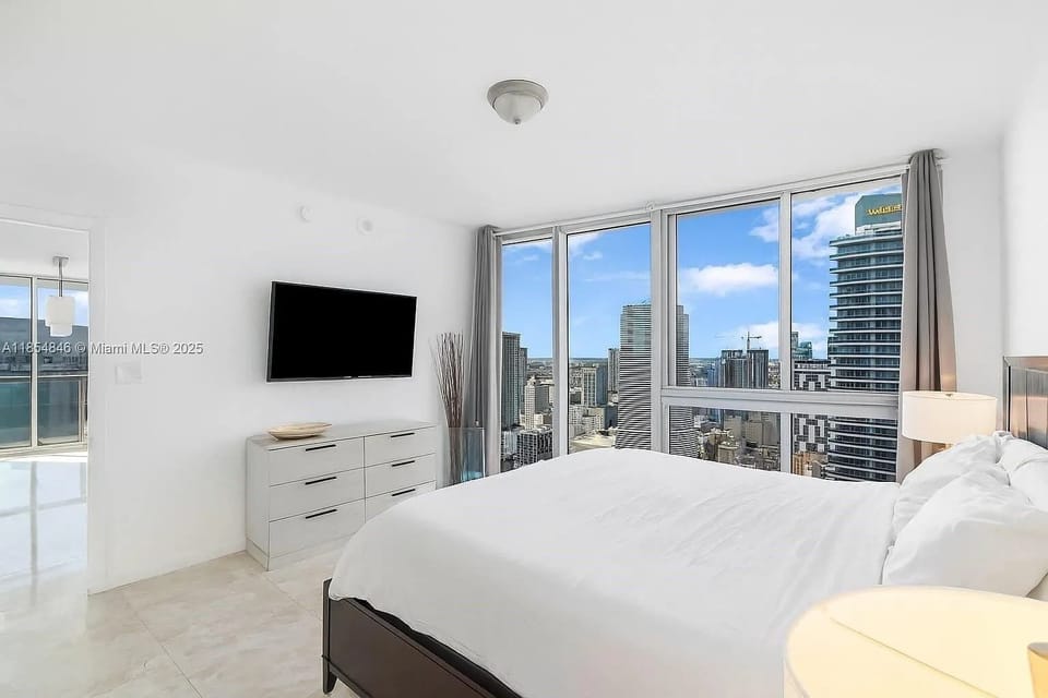 Sun-drenched bedroom featuring a wall-mounted TV and chic decor.