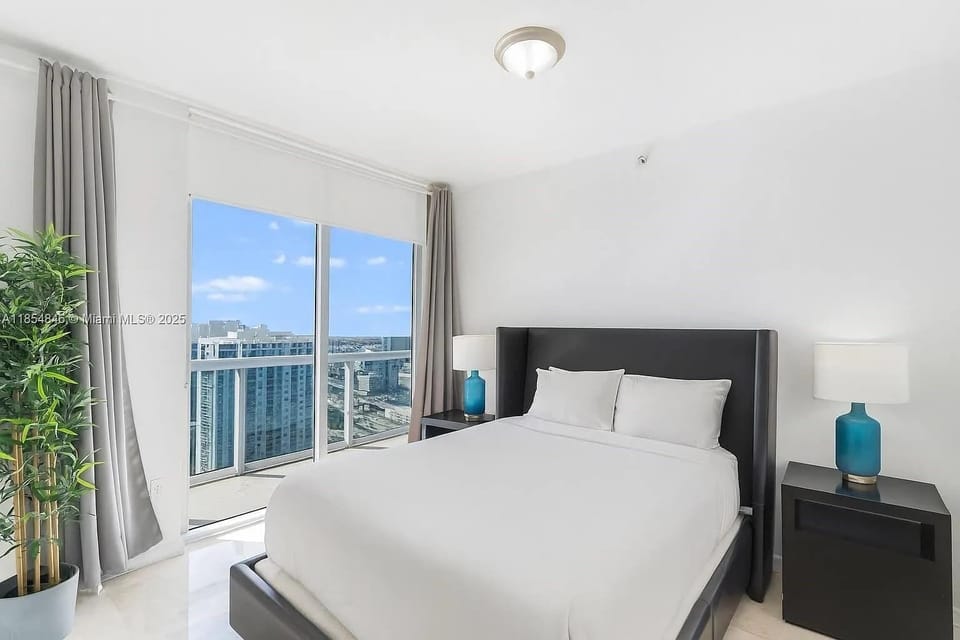 Elegant second bedroom with plush bedding and private balcony access.