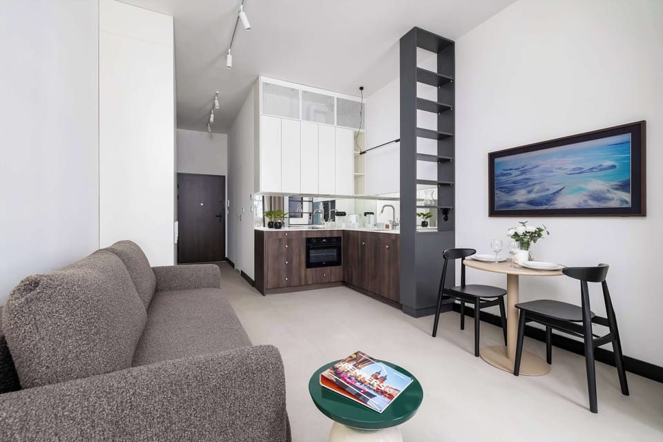 Bright perspective showing dining area, kitchenette, and sleeping zone in one open space.
