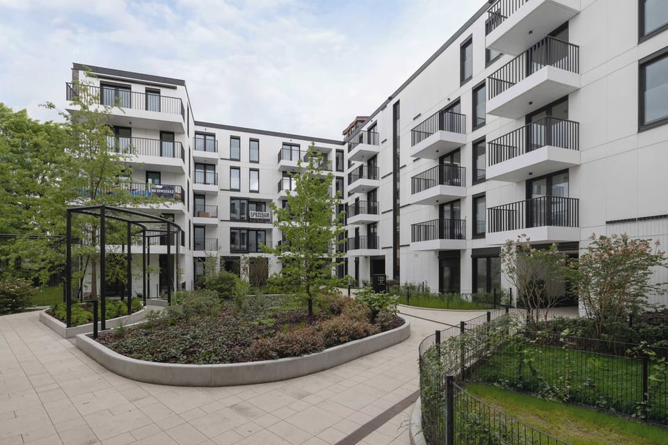 Green residential courtyard surrounded by modern apartment buildings.