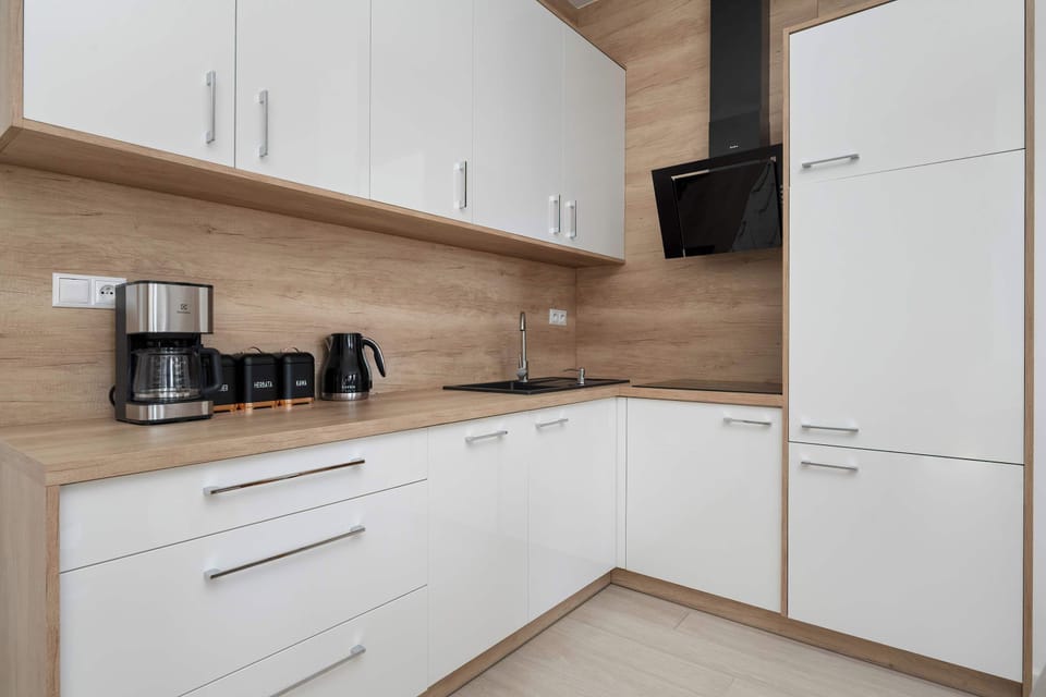 Modern kitchen with white cabinetry, wooden accents, and built-in appliances.