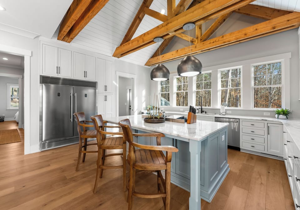Gourmet kitchen with a large island, blue cabinetry, and vaulted wood-beamed ceilings.