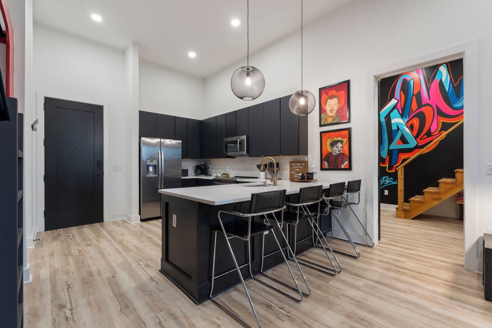 Sleek, modern kitchen with a spacious island, bar seating, and statement lighting—ideal for casual meals or pre-show hangouts.