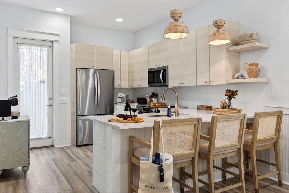 Modern kitchen view showing the breakfast bar with seating and stainless steel appliances.