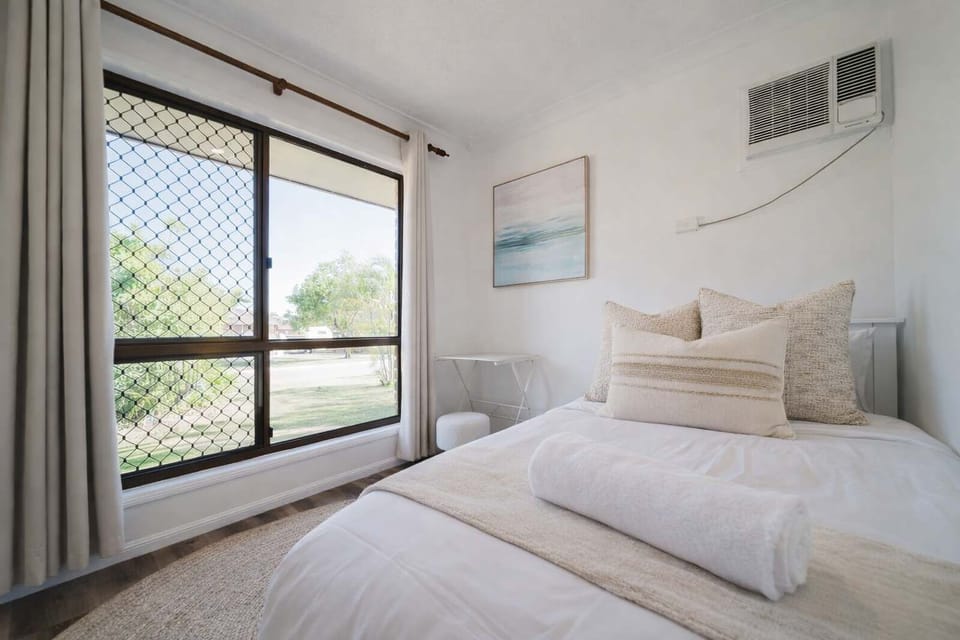 Light-filled bedroom with soft furnishings, air conditioning, and a peaceful atmosphere