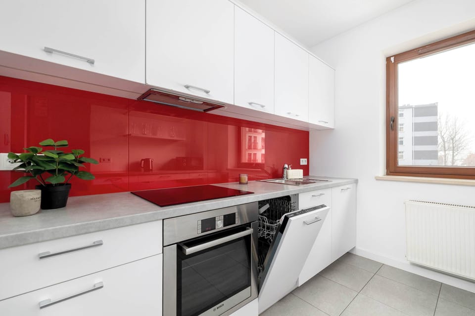 Modern kitchen with red backsplash and window.