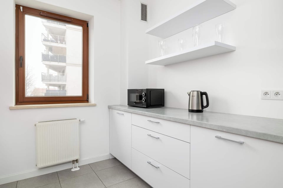 White kitchen with kettle, microwave, and storage.