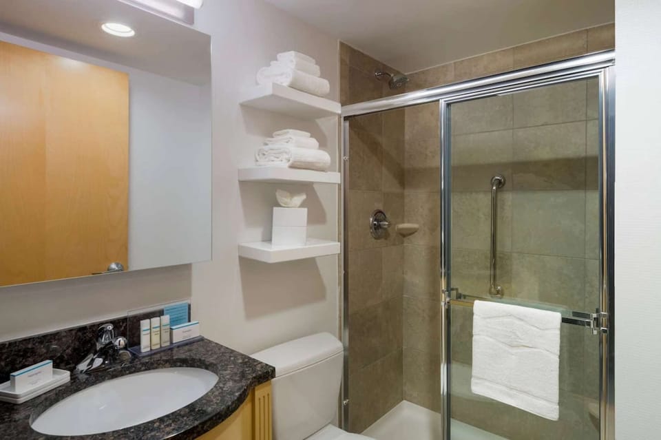 Bathroom with glass shower, sink, and fresh towels ready
